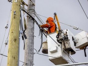 Brad Sipila, a power line worker for London Hydro switches lines from an old pole to new on Gainsborough Road in London, Ont. on Monday April 11, 2022. (Mike Hensen/The London Free Press)