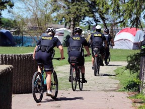 About a dozen Sarnia police officers ride past the homeless encampment in Rainbow Park on May 8, 2024. (Terry Bridge/The Observer)