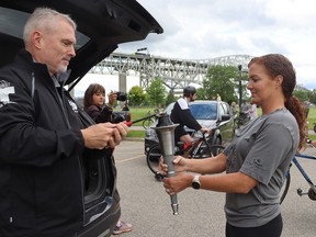 Derek Spence with the Law Enforcement Torch Run for Special Olympics, lights a torch held by Jocelyne Paquette, with Sarnia police, before Friday's run in Point Edward.