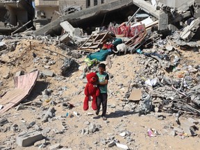 A Palestinian child walks with a stuffed bear recovered from the rubble of a destroyed building following Israeli bombardment in Khan Yunis on June 21, 2024, in the southern Gaza Strip, amid the ongoing conflict in the Palestinian territory between Israel and Hamas.