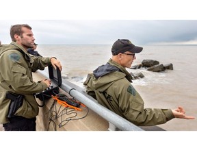 Matthew Duquette and Chris Weise of the Ontario Provincial Police underwater search and recovery unit used a radio to communicate with diver Al Jozwiak while searching at Port Stanley for a 14-year-old London swimmer who disappeared one day prior.  Photo taken on July 15, 2024. Mike Hensen/The London Free Press