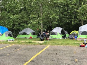 Tents that once lined the wall of Talbot Gardens arena in downtown Simcoe now sit on the banks of the Lynn River on county-owned property behind a vacant building.
