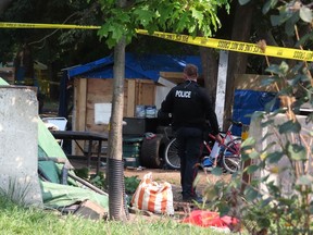 A Kingston Police officer walks through the encampment off Montreal Street in Kingston, Ont., on Thursday, September 12, 2024 after two people were killed and another seriously injured.