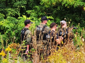 Kingston Police officers set up in a wooded area as they respond to an incident near the Integrated Care Hub on Montreal Street. Elliot Ferguson/The Kingston Whig-Standard