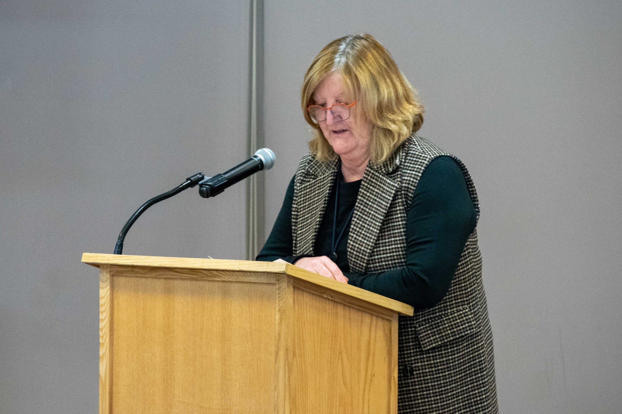 Higgs stands at a podium.