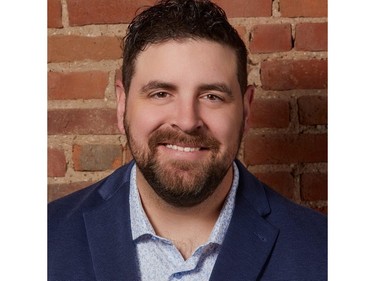 A man with brown hair and a a short beardsmiling at the camera