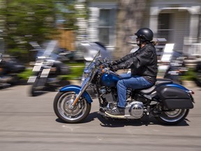 A motorcyclists rides down a road on a sunny day.