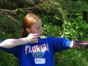 Kim Bishop aims a bow and arrow
