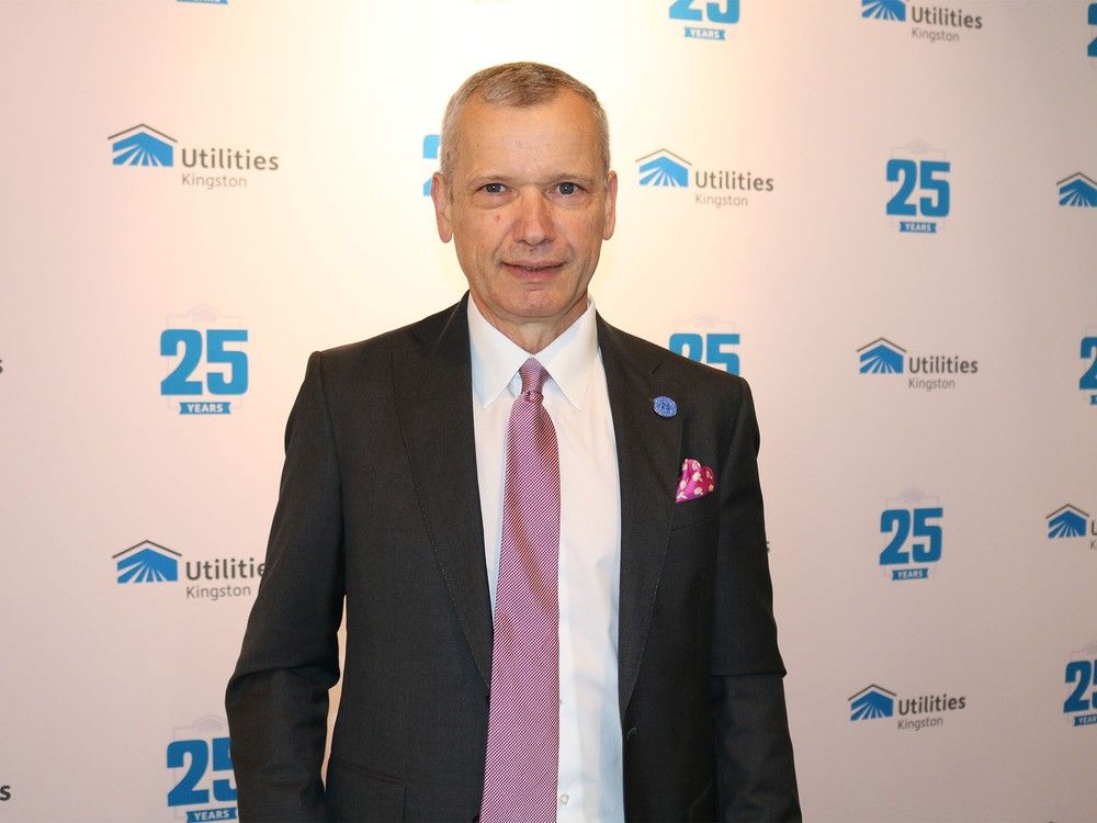 A man wearing a black suit and pink tie, smiling
