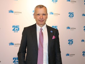A man wearing a black suit and pink tie, smiling