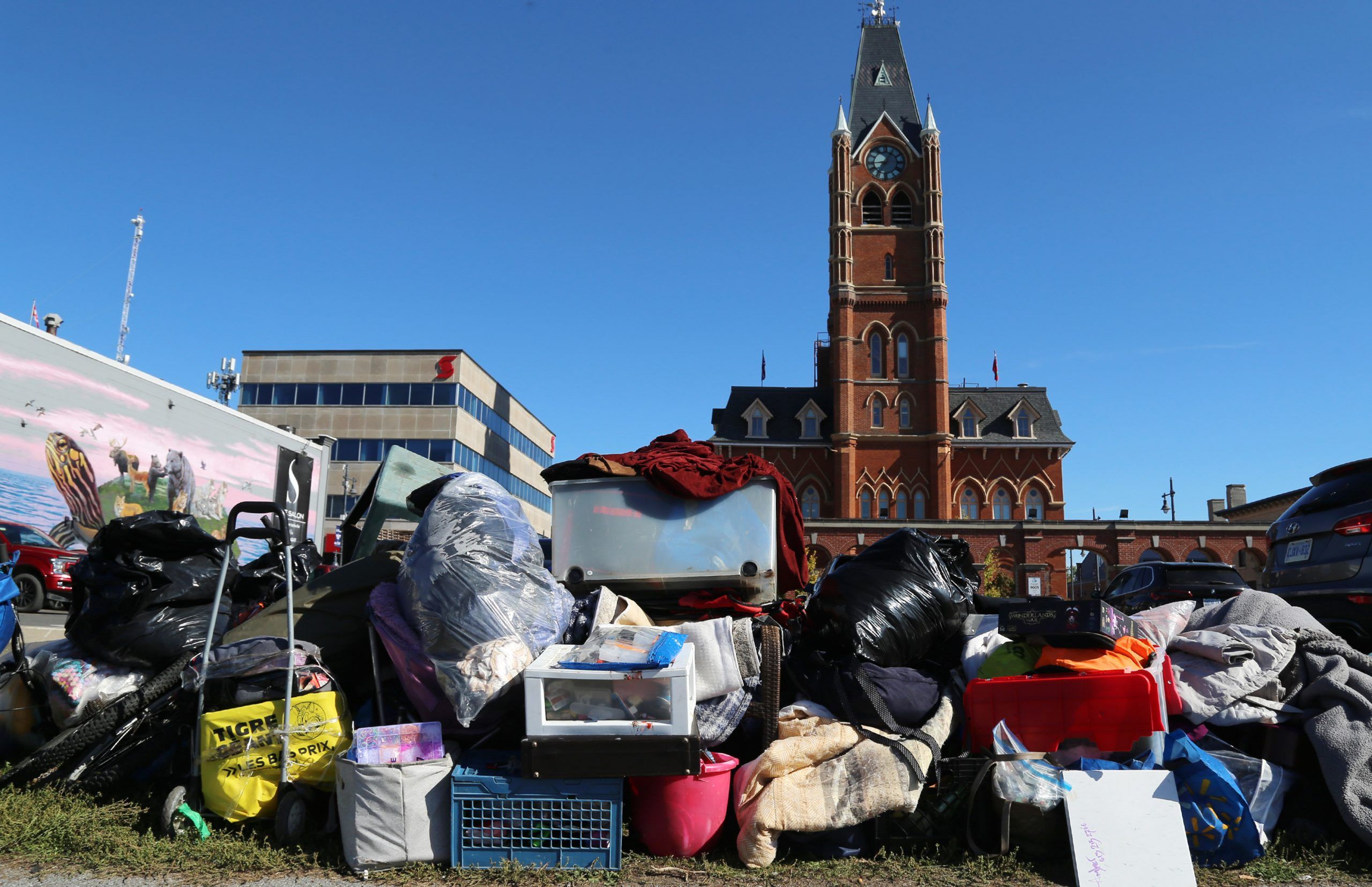 Encampment residents' belongings await relocation by their owners Tuesday, Oct. 14, 2025 near city hall, background, in Belleville, Ont. Authorities allowed residents to pack and move prior to public works staff cleaning up the site. (Luke Hendry/The Belleville Intelligencer/Postmedia Network)