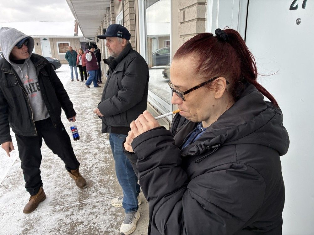 tammy ball lights a cigarette outside the motel room where she and her partner paul wensing have been staying since a downtown fire forced them out of their apartment in kingston, ont. on wednesday, nov. 3, 2024. (photo by elliot ferguson/the whig-standard/postmedia network)