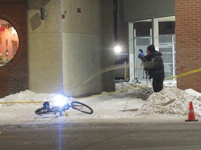 A Kingston police officer photographs the scene of a collision involving a cyclist at the intersection of Princess Street and Drayton Avenue in Kingston, Ont. on Friday, Jan. 23, 2026. (Photo by Elliot Ferguson/The Whig-Standard/Postmedia Network)