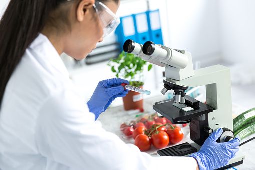 Female microbiologist using microscope in laboratory