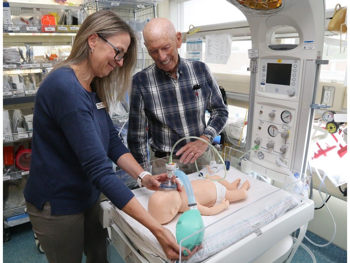 Man smiles as woman puts breathing mask on infant doll
