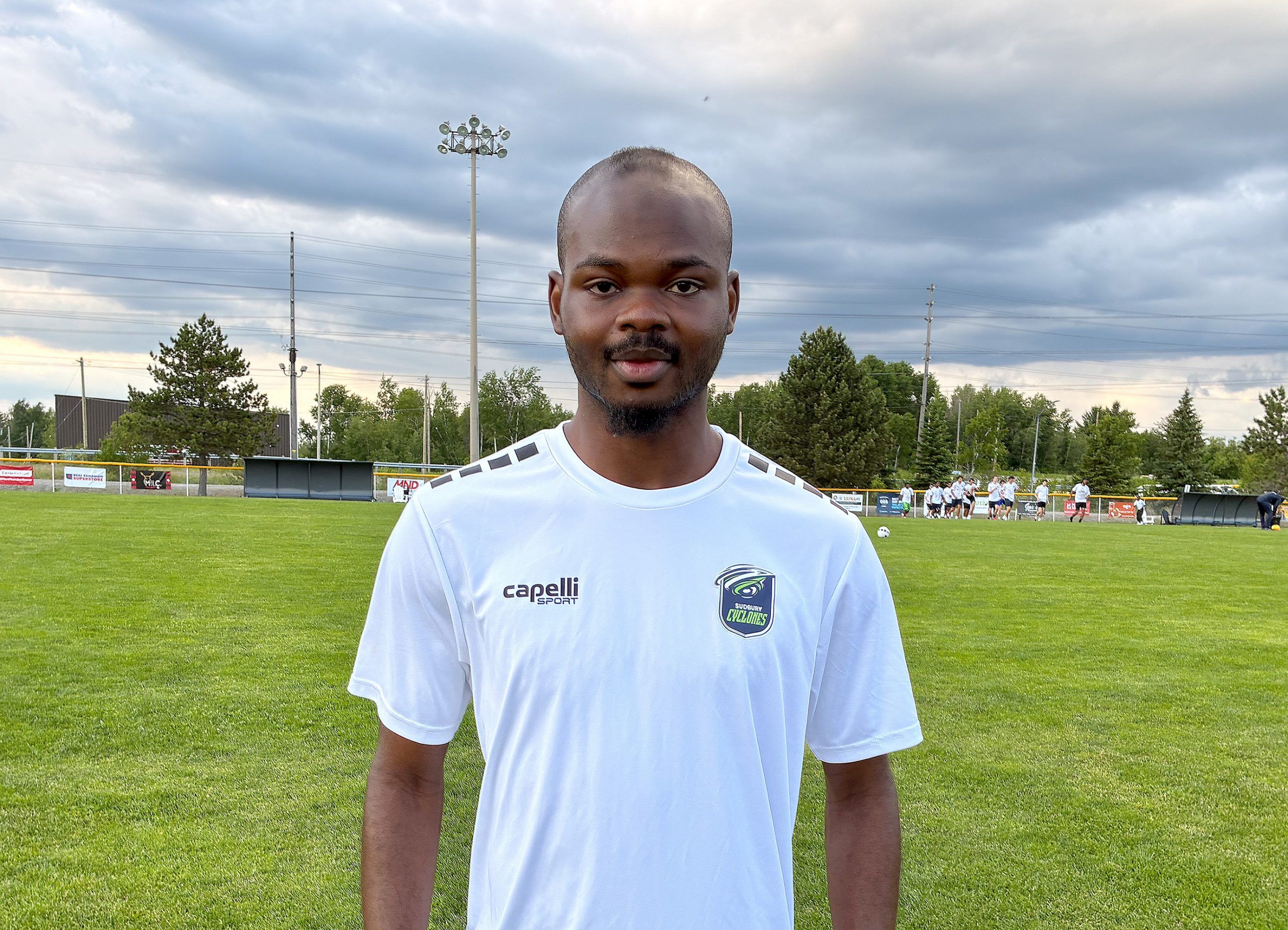 Aziz Traore poses for a photo beside a soccer field