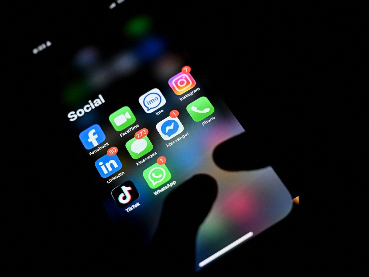 A man uses a smartphone as various social media apps are displayed on screen in Pugoda on June 12, 2026.