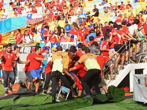 Security personnel try to control Chilean fans on the field of play entering the stands.  (Photo by David Ramos/Getty Images)