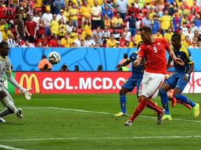 Switzerland's forward Haris Seferovic (R) scores past Ecuador's goalkeeper Alexander Dominguez during a Group E football match between Switzerland and Ecuador at the Mane Garrincha National Stadium in Brasilia during the 2014 FIFA World Cup on June 15, 2014. Switzerland won 2-1.    AFP PHOTO/ ANNE-CHRISTINE POUJOULATANNE-CHRISTINE POUJOULAT/AFP/Getty Images