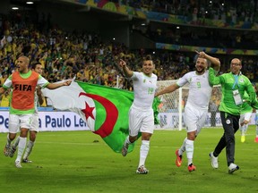 Algeria's midfielder Saphir Taider (C), Algeria's forward Nabil Ghilas (2nd R) and Algeria's defender Madjid Bougherra (front L) celebrate at the end of their Group H football match against Russia at the Baixada Arena in Curitiba during the 2014 FIFA World Cup on June 26, 2014.     AFP PHOTO / ADRIAN DENNISADRIAN DENNIS/AFP/Getty Images