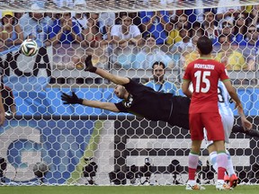 Iran's goalkeeper Alireza Haghighi dives but fails to stop a goal by Argentina's Lionel Messi during the group F World Cup soccer match between Argentina and Iran at the Mineirao Stadium in Belo Horizonte, Brazil, Saturday, June 21, 2014. Argentina defeated Iran 1-0. (AP Photo/Martin Meissner)