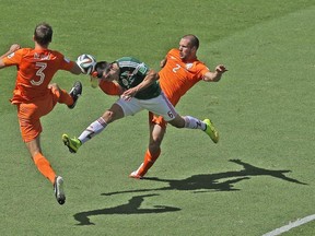 Mexico's Hector Herrera, center, challenges for the ball with Netherlands' Stefan de Vrij, left, and Ron Vlaar during the World Cup round of 16 soccer match between the Netherlands and Mexico at the Arena Castelao in Fortaleza, Brazil, Sunday, June 29, 2014. (AP Photo/Themba Hadebe)