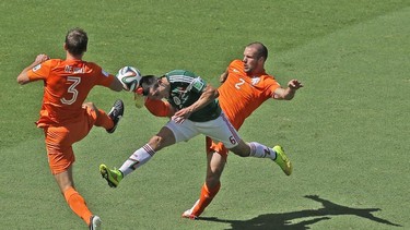 Mexico's Hector Herrera, center, challenges for the ball with Netherlands' Stefan de Vrij, left, and Ron Vlaar during the World Cup round of 16 soccer match between the Netherlands and Mexico at the Arena Castelao in Fortaleza, Brazil, Sunday, June 29, 2014. (AP Photo/Themba Hadebe)