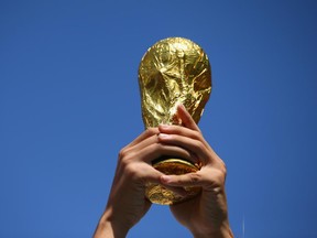 A fan holds up a replica of the World Cup trophy prior to the 2014 FIFA World Cup Brazil Group B match between the Netherlands and Chile at Arena de Sao Paulo on June 23, 2014 in Sao Paulo, Brazil.  (Photo by Julian Finney/Getty Images)