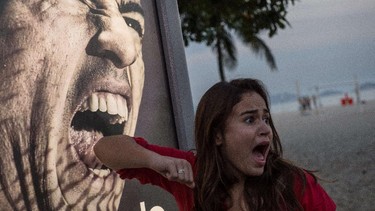 A tourist jokes in front of an advertisement with the portrait of Uruguay's forward Luis Suarez at Copacabana beach in Rio de Janeiro, Brazil, on June 26, 2014. Sportswear giant Adidas said Thursday it would stop using Luis Suarez, one of its key promotional stars, for World Cup adverts after his four-month ban from football activities for biting Italian Giorgio Chiellini. YASUYOSHI CHIBA/AFP/Getty Images