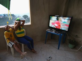 Veronica Silva and her son, Gustavo Silva, living in the favela known as Falete, watch Brazil play against Mexico on television as the FIFA World Cup tournament continues on June 17, 2014 in Rio de Janeiro.  (Joe Raedle/Getty Images)