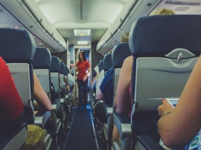Flight attendant standing between passenger seats.