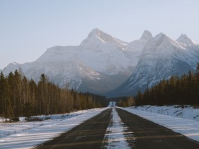 A photo of the Icefields Parkway highway in Jasper National Park, with snowy mountains in the background.