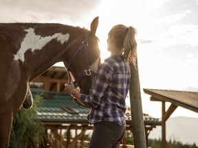 A woman gets a horse ready for a group trail ride at the Myra Canyon B&B (Kelowna Stables), outside of Kelowna, BC. [Keri Medig/Destination BC]