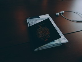 Canadian passport beside earphones on surface