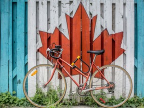 Red road bike beside red and white wooden maple leaf painted wall. (Photo by Ali Tawfiq on Unsplash)