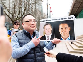 Protester Louis Huang of Vancouver Freedom and Democracy for China holds photos of Canadians Michael Spavor and Michael Kovrig,