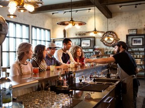 A group of people sit at the bar at Eau Claire Distillery in Turner Valley, Alberta