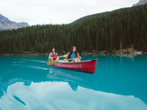 Two people paddle a canoe in Moraine Lake in Banff, Alberta