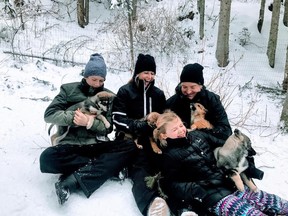 Melissa Vroon, middle, and her family play with puppies from Mountain Man Dog Sled Adventures at Sun Peaks Resort in British Columbia