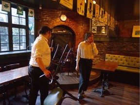 Teagan Kum-Sing, right, and Zach Oskrdal put chairs away at Hurleys, which has closed because of the government mandate to shut down bars in hope of preventing the spread of the novel coronavirus.