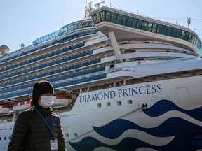 A member of the media wearing a face mask walks past the Diamond Princess cruise ship at Daikoku Pier Feb. 10, 2020 in Yokohama, Japan.