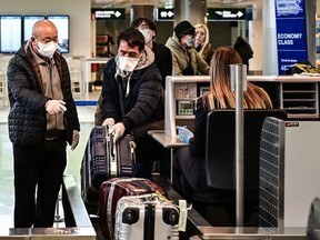 Passengers wearing a respiratory mask check in at Milan-Malpensa airport in Ferno, northwest of Milan, in one of Italy's quarantine red zones on March 9, 2020.