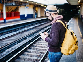 Man holding cell phone at train station