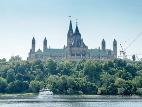 The Peace Tower and Parliament Hill rise majestically over the Ottawa River.
