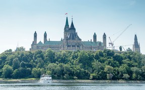 The Peace Tower and Parliament Hill rise majestically over the Ottawa River.