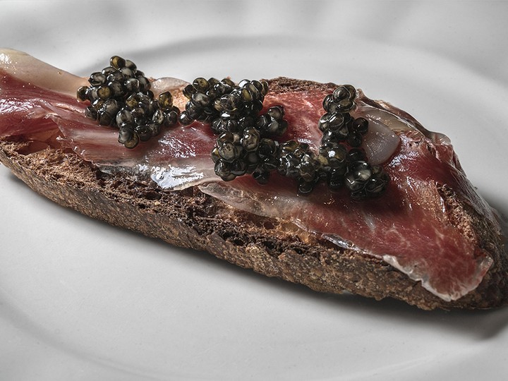  A slice of caviar-topped acorn-fed IbÈrico ham on a piece of bread.