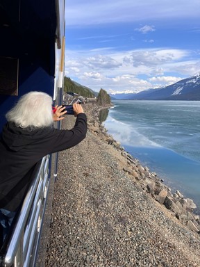 An image of a person taking a photo from the open-air vestibule on the Rocky Mountaineer Train in the Canadian Rockies in Canada.