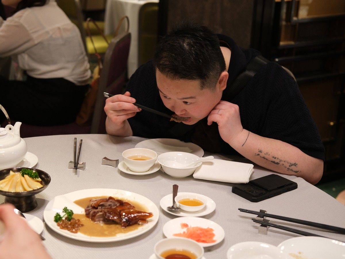Chin taking a bite of charcoal-roast goose at Yung Kee.
