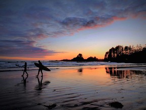 People walk along the shore at Cox Bay Beach in Tofino.