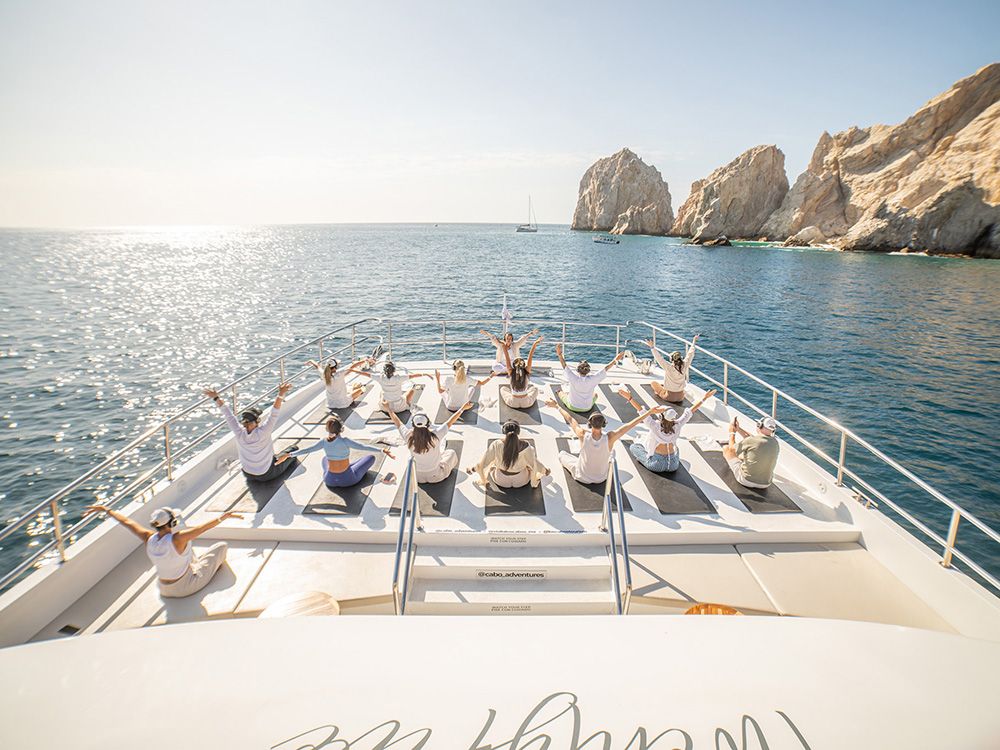 Morning yoga on the Sea of Cortez, with the iconic Arch of Los Cabos in the background.